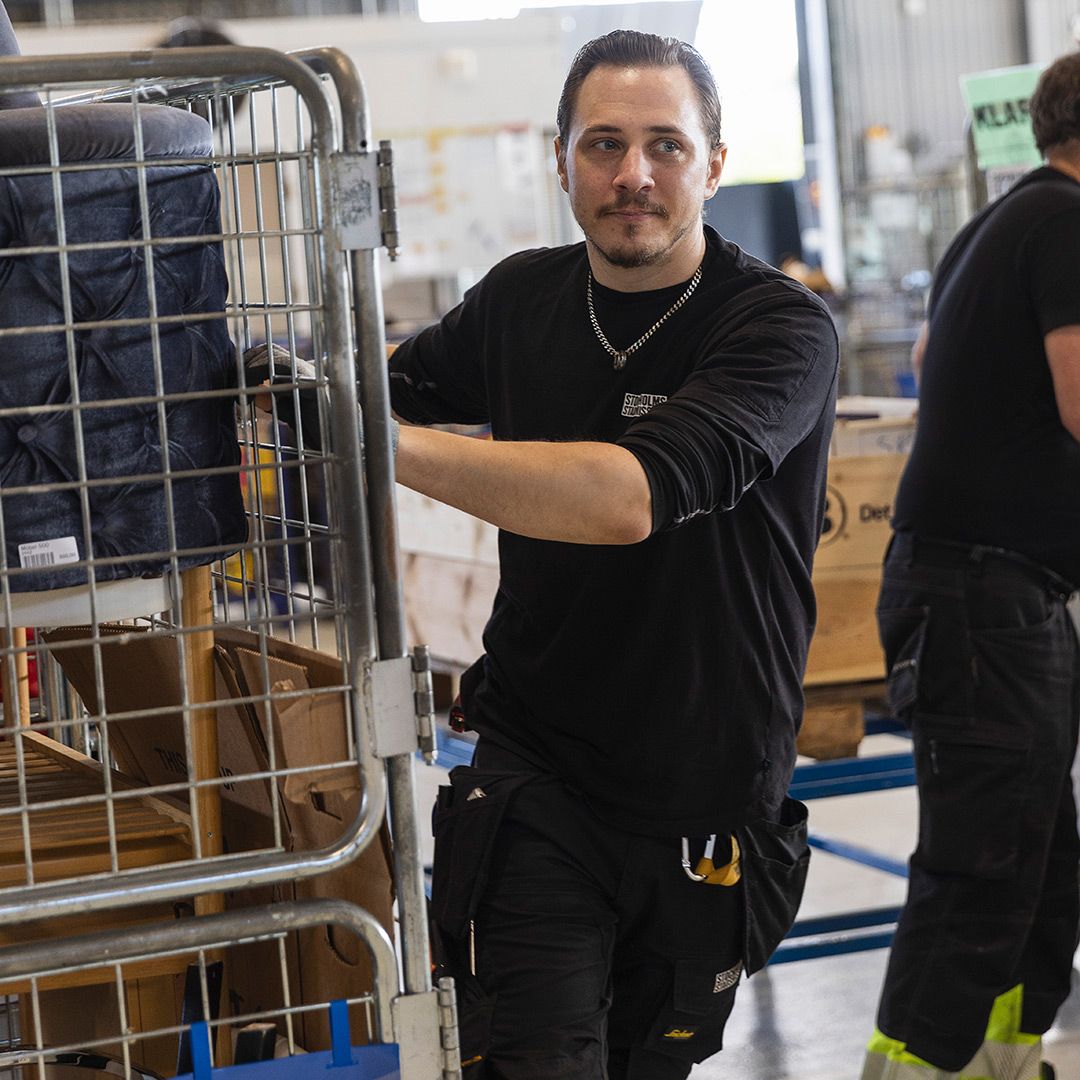 Medarbetare drar en vagn på Stockholms Stadsmissions insamlings-och produktionsenhet.
