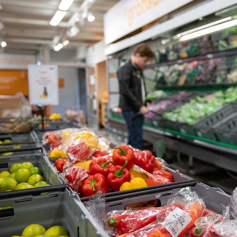 Grönsaksdisken i en Matmissionenbutik. I bakgrunden en man som handlar. 